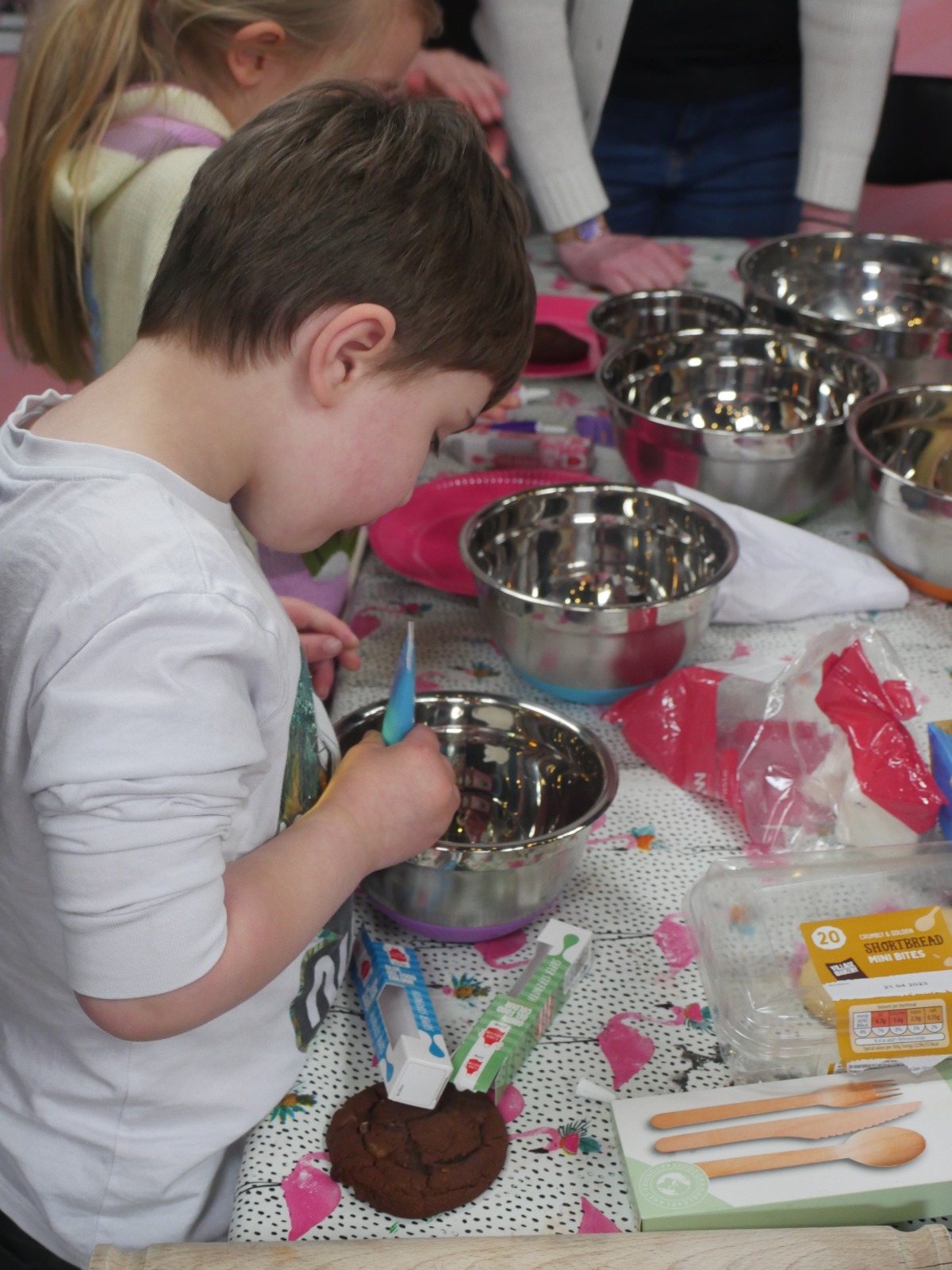 Child squirting food colouring into a bowl to mix icing.