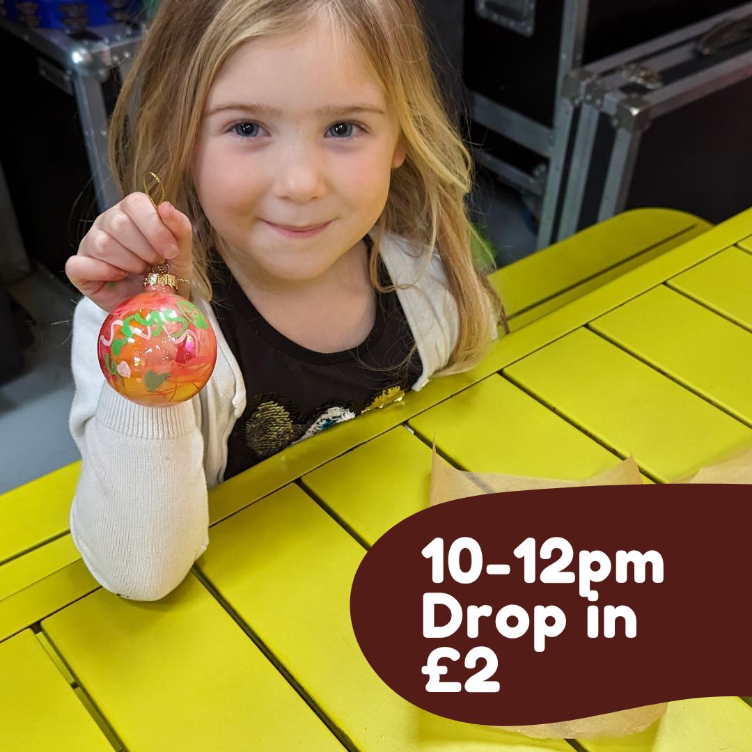 Little girl holds up a bauble she has painted