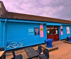 Bright blue clubhouse with pink accents and a painted wave